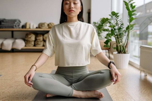 Une femme assise en studio se concentre sur sa respiration yogique les yeux fermés.